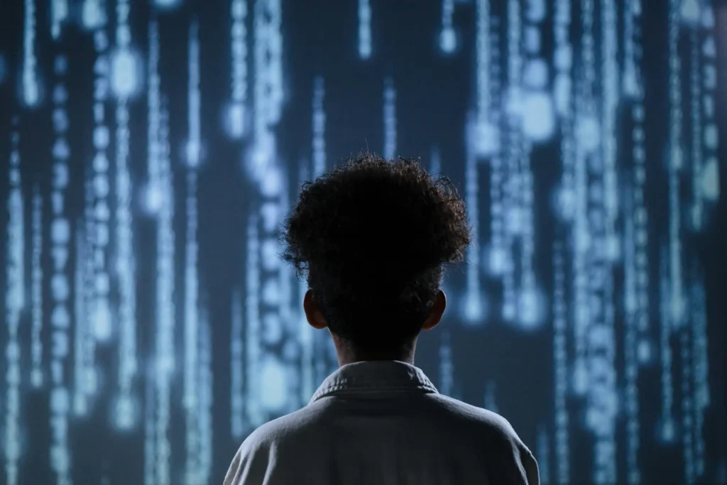 A young boy in a doctors coat stand in front of a stream of data falling in light streams from the sky. The feeling is one of hope for the future. 