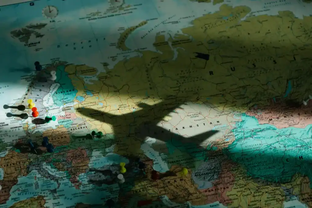 A shadow of a plane is cast upon a map of the world, which is partially in complete shadow. It suggests an interconnected world but not one without issues.